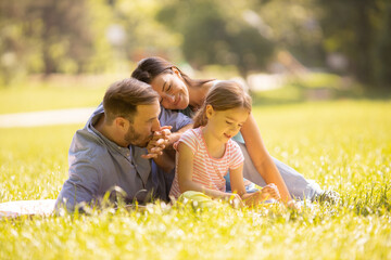 Happy young family with cute little daughter having fun in the park on a sunny day