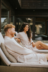 Naklejka premium Young couple relaxing on beds on the outdoor terrace