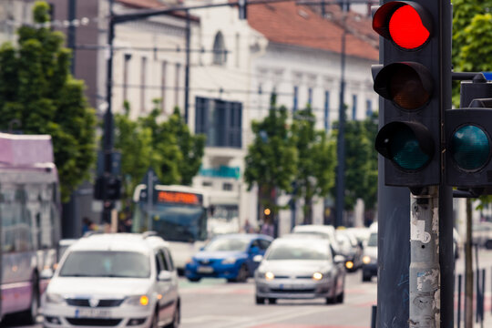 Semaphore with red light on and busy traffic in the background with blurred cars and bus