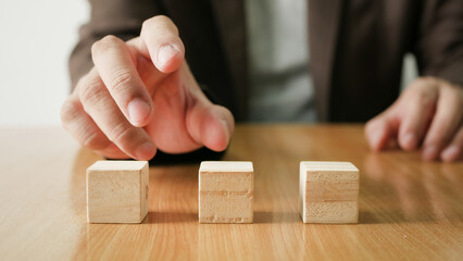 Businessman choosing a row of square wooden blocks on a wooden table. Business development concept...