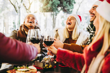 Happy family wearing santa claus hat having Christmas dinner party- Cheerful group of friends...