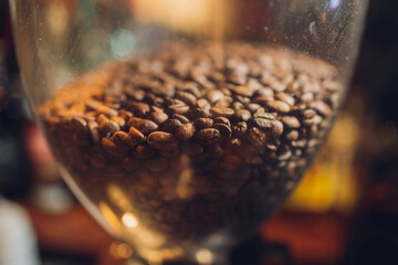Glazen bank met koffiebonen kosten op een tafel op een zwarte achtergrond.