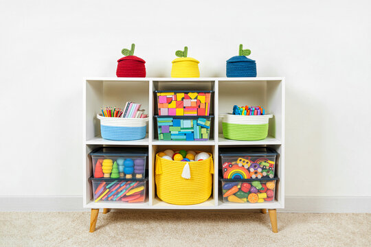White shelving with rainbow wooden toys and colorful storage baskets and boxs. Interior design. Organizing and storage ideas in nursery.