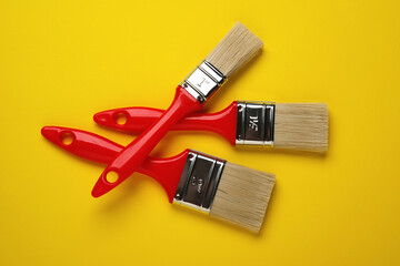 three paint brushes on yellow background - closeup
