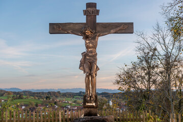 Der gekreuzigte Jesus an einem Holzkreuz am Kloster Andechs mit Himmel, Horizont und dem...