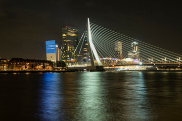 Fototapeta na wymiar Erasmusbrug cable-stayed bridge over the Maas river in the center of Rotterdam with city view and reflection at night