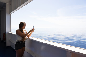 Tourist Taking Selfie with her smartphone smiling in a ferry boat