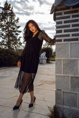 Young Mongolian woman in black dress stand by the wall in Ulaanbaatar city. Asian fashion concept.