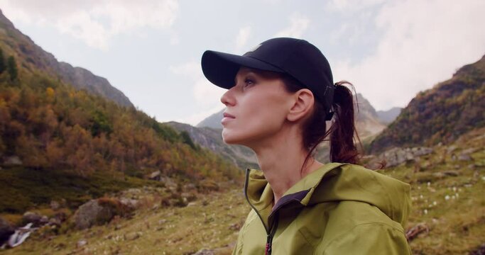 Young Hiker Woman in green raincoat looking around autumn highland and mountains in breack hike. Close-up view