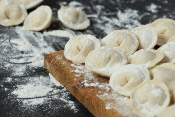 Uncooked homemade meat pelmeni. Pelmeni on dark table