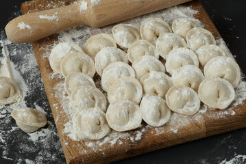 Uncooked homemade meat pelmeni. Pelmeni on dark table