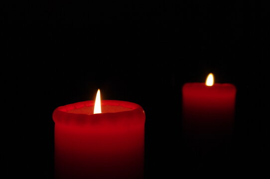 Two red candles on a dark background, emphasizing the flame