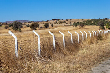  Fencing of white poles with barbed wire in the field.