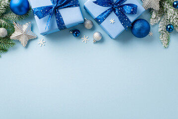 Christmas concept. Top view photo of trendy gift boxes with bows blue and silver baubles sparkle star ornaments pine branches in snow and confetti on isolated pastel blue background with copyspace