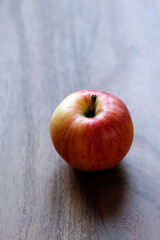 isolated red and yellow apple on a wooden table with space for text, vertical format