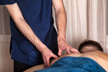 Fototapeta na wymiar Masseur hands doing sports wellness massage for man patient in medical room. Therapeutic regenerating massaging of sports body. Concepts of rehabilitation of sport injuries. Copy text space