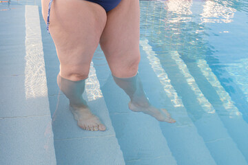Mature plus size woman walks down the steps to the pool. fiberglass plastic swimming pool entrance...