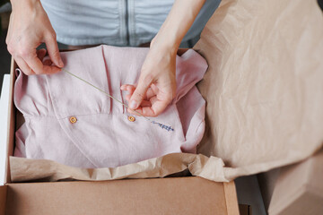 woman packs children's clothes, a pink dress in boxes. small business and entrepreneurship. a...