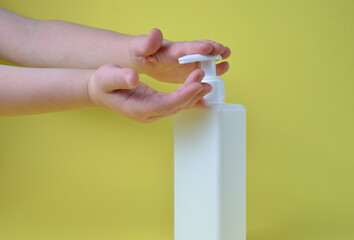 The hands of the child press the bottle of soap.