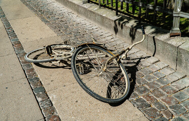 Obraz premium An old dirty bicycle lies in the middle of the street.