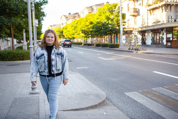 Obraz premium Beautiful plump woman wearing jeans and t-shirt posing against the street in the city next to the road