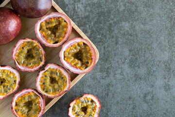 Whole and halves of fresh passion fruit on a wooden board. Background of exotic Asian fruits. Gray background, copy space.