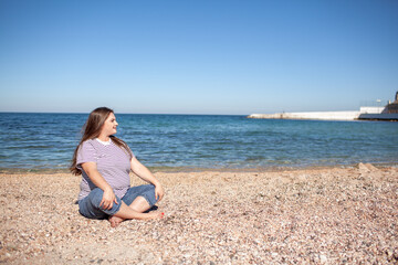 Fototapeta na wymiar Beautiful plus size woman walking in the beach, resting and enjoy the moment to be alone and meditate near the sea or ocean in the beach. Overweight woman dressed jeans and t-shirt