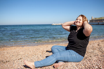Fototapeta na wymiar Beautiful plus size woman walking in the beach, resting and enjoy the moment to be alone and meditate near the sea or ocean in the beach. Overweight woman dressed jeans and t-shirt