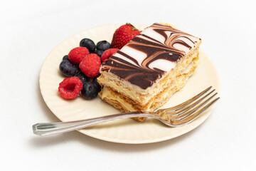 Napoleon dessert pastry and colorful mixed berries plated with silver fork.