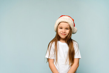 Funny cute baby girl in santa hat on blue background. Christmas and New Year concept