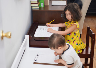 Little boy copying his sister doing her homework