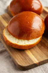 Homemade Brioche Hamburger Buns on a wooden board, side view. Close-up.