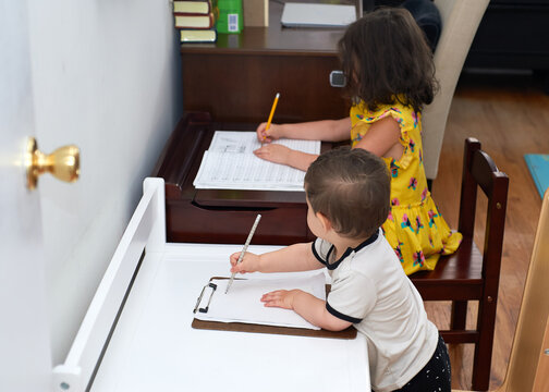 Little Boy Copying His Sister Doing Her Homework