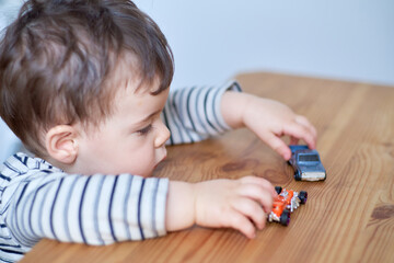 cute toddler playing with his toy cars on the table