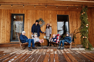 Big young family with four kids on the terrace of a wooden house in winter day.