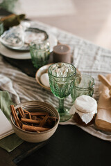 Festive Christmas table setting. Green glass glasses and cinnamon sticks in a clay plate on the table