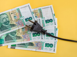 Black electric plug on one hundred bulgarian lev banknotes. Rise in energy prices in Bulgaria....