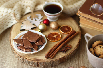 Cup of tea or coffee, various sweets and spices, Christmas decorations, comfy blanket, books and glasses. Selective focus.