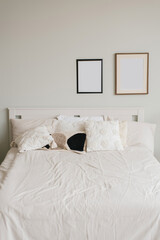 Bed in the bedroom in a Scandinavian minimalist style. Light pillows on the bed. Decor above the bed frame mockups