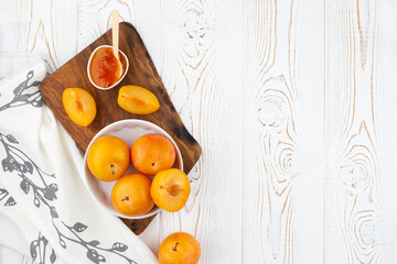Plum jam in a bowl and yellow plums, plum slices on a wooden board on a white rustic table, napkin. Copy space, flat lay