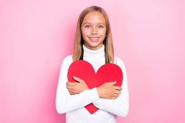 Photo of adorable cheerful girl hands hold embrace red paper heart card isolated on pink color background
