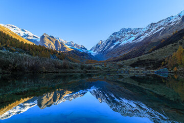Fototapeta na wymiar Grundsee Lake in the Fafleralp Valley at the sunrise time with reflection of the surrounding Alps mountain peaks and the Long Glacier
