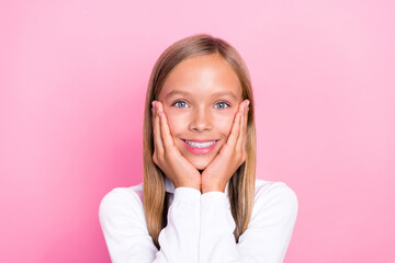 Photo of positive lovely girl arms touch cheeks beaming smile isolated on pink color background
