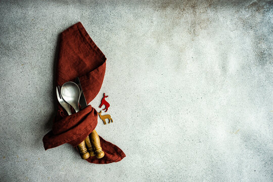Overhead view of a rustic Christmas cutlery set wrapped in a napkin with reindeer decorations - Powered by Adobe