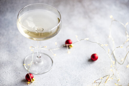 Close-Up of a Glass of champagne wine decorated with string lights and Christmas baubles