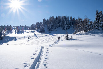 two ski tourers in sunny, deep snowy winter landscape