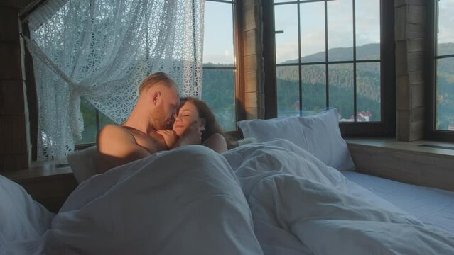 Couple cuddling on bed in morning