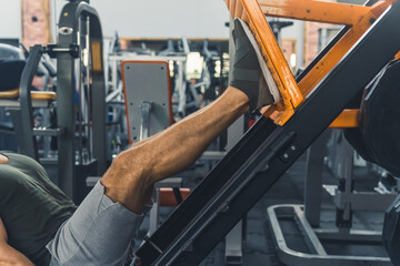 Professional gym leg press used by unrecognizable caucasian person in gray shorts. Body muscles...