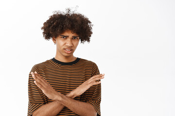 Portrait of guy showing stop, refusal gesture, rejecting smth with dislike face expression,...
