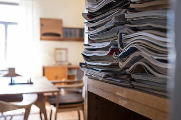 Paper notebooks used and stacked on a rack shelf, cozy office.